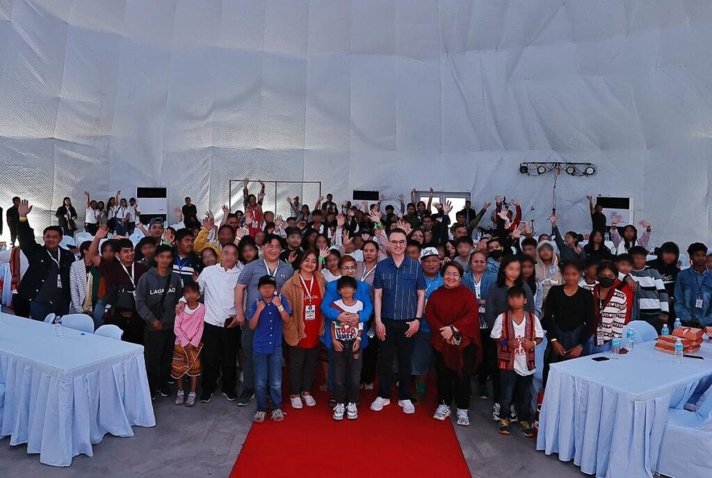 Alan Peter Cayetano poses with a large group, hands raised, fostering community, showing support, and engaging at a public event.