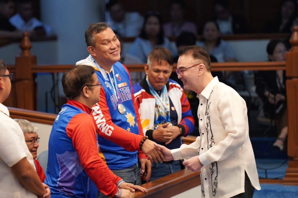 Alan Peter Cayetano shakes hands with sports figures, showing support, engaging with athletes, and promoting sportsmanship at a public event.
